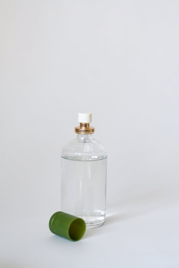 Elegant glass perfume bottle with a green cap on a light backdrop, showcasing simplicity.